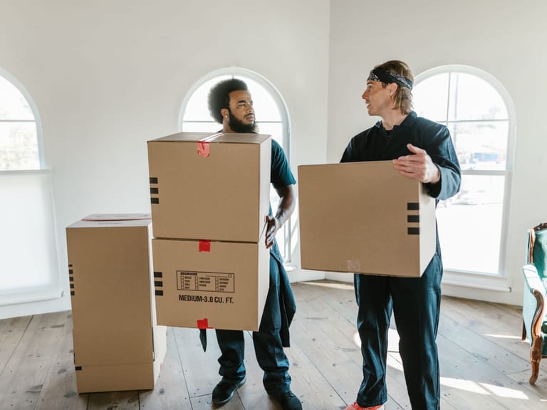 Zwei Mitarbeiter tragen Kartons bei einer Wohnungsentrümpelung durch einen hellen Raum