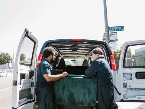 Zwei Mitarbeiter laden ein Sofa in einen Transporter